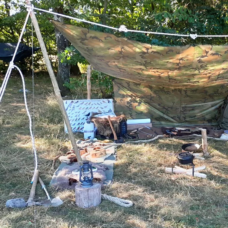 Lager mit Tarp, Kochstelle und Ausrüstung im Wald